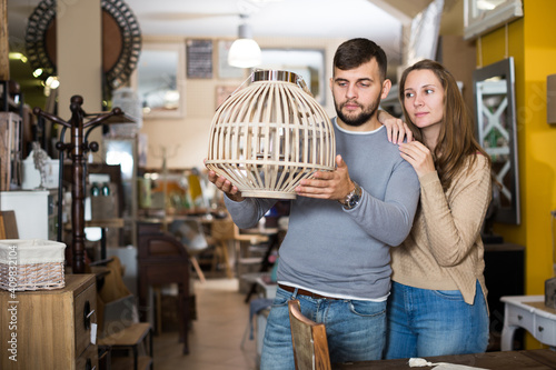 Loving couple looking for stylish hanging lamp in shop of secondhand furniture