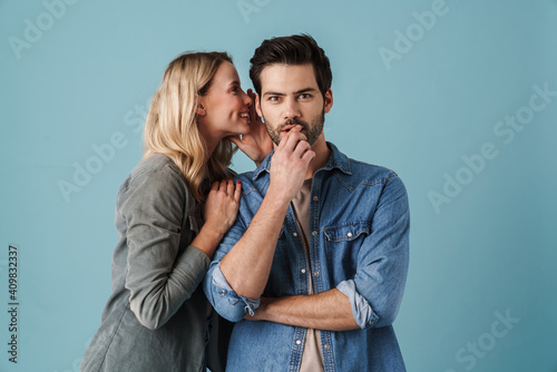 Young beautiful woman whispering secret at surprised guy