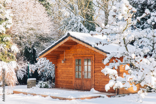 Wooden garden shed covered with snow. First snow. Winter in the garden