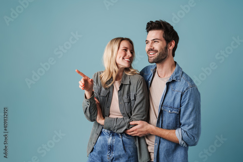 Young beautiful excited man and woman hugging and pointing finger