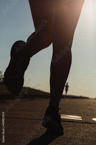 Running foot athlete running on the road - Fitness silhouette exercising at sunset.