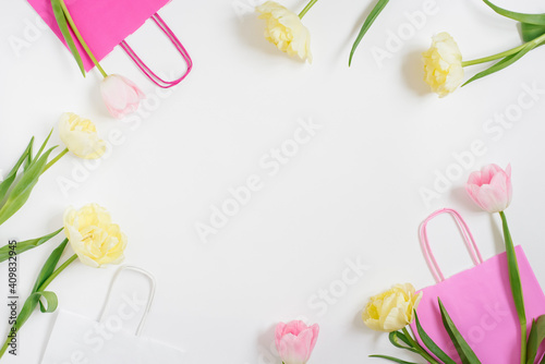 Spring tulip flowers and gift box on light table top view in flat lay style. Greeting card for Birthday, Valentine Woman or Mothers Day
