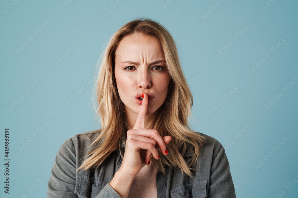 Displeased beautiful girl looking at camera and showing silence gesture Displeased beautiful girl looking at camera and showing silence gesture