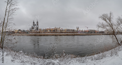 Fototapeta Naklejka Na Ścianę i Meble -  Panoramic view over Magdeburg historical downtown in Winter with icy trees and snow during foggy day and dramatic sky, Germany.