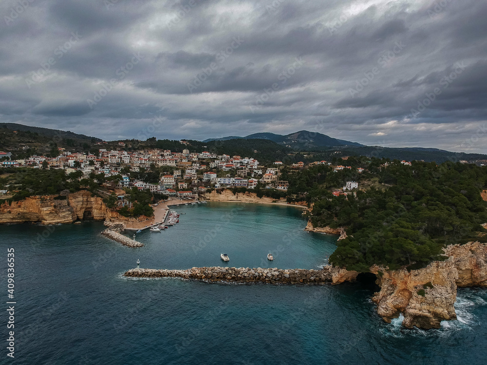 Aerial view over Votsi beach (Paralia Votsi) and the picturesque port with traditional wooden fishing boats in Alonnisos island during Winter period in Sporades, Greece