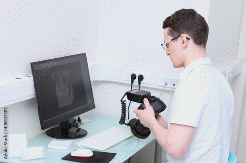 The dentist views the 3D image of the teeth on the computer. A camera with a ring flash in the hands of a doctor. Modern dental office.