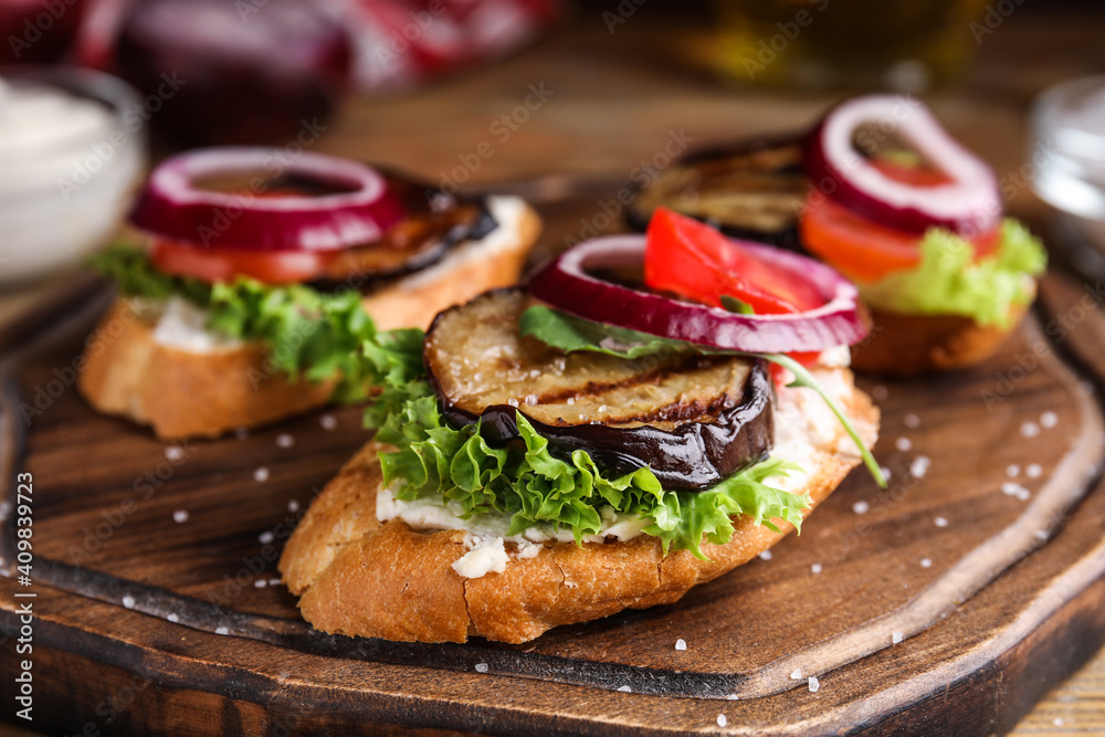 Delicious eggplant sandwiches served on wooden board, closeup