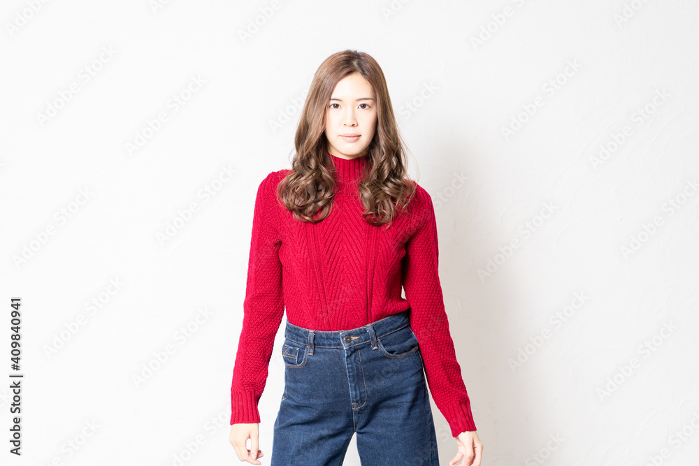 白い壁の前に立って、ポーズをとる赤いセーターを着た若い女性 白い壁の前に立って、ポーズをとる赤いセーターを着た若い女性