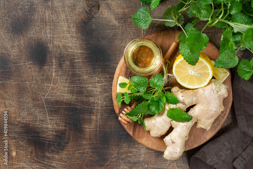 Ingredients for ginger tea with lemon, honey and mint. Lemon, ginger, honey and lemon balm on the table. Healthy food to boost immunity. Ingredients for ginger cookies with honey and mint. Top view 