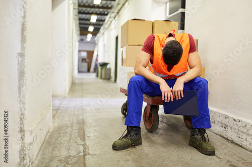 Arbeiter sitzt erschöpft auf einem Schubwagen photo