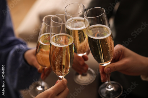 People clinking glasses with champagne at home, closeup