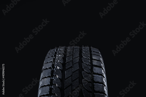 Winter tire on black background, closeup. Car maintenance
