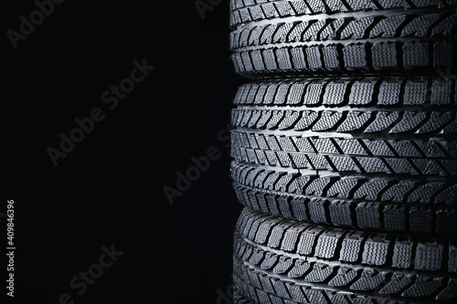 Stacked winter tires on black background  closeup. Space for text