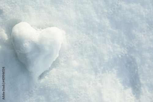Heart shaped snowball on snow, top view. Space for text