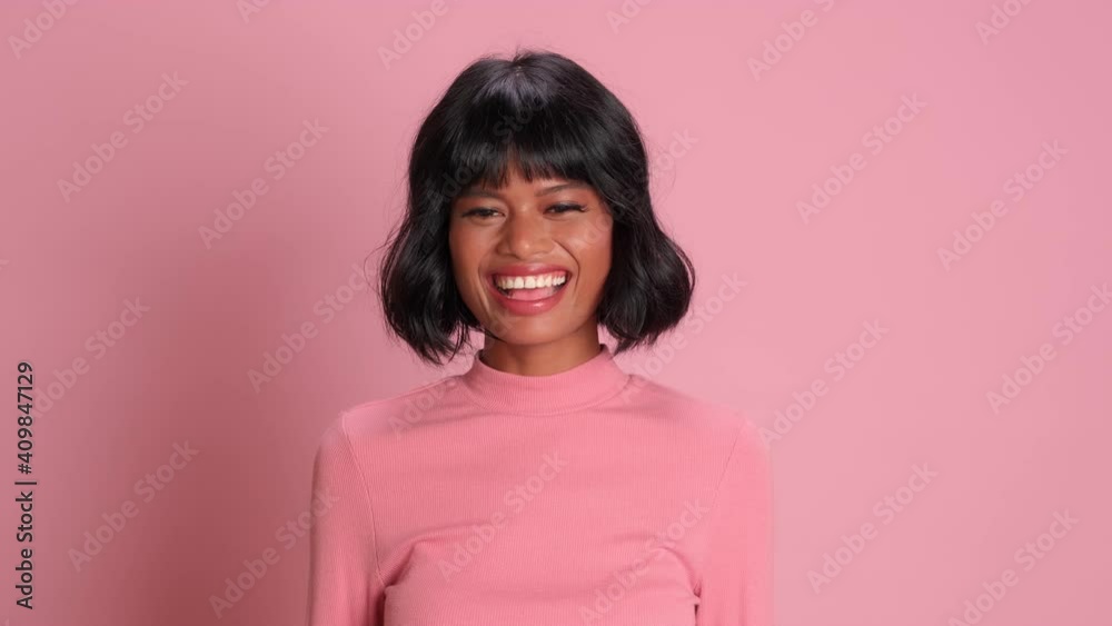 Facial emotion. Close up of playful dark skinned woman flirting and winking on pink background. Positive brunette woman posing in studio. Concept of expressive facial expressions. Facial emotion. Close up of playful dark skinned woman flirting and winking on pink background. Positive brunette woman posing in studio. Concept of expressive facial expressions.