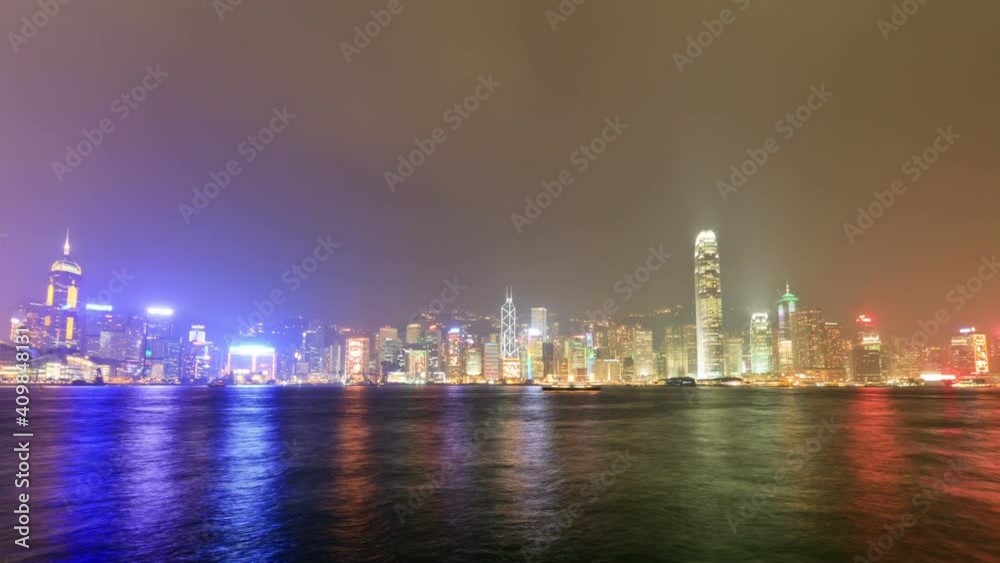 Hong Kong city skyline at night with Victoria Harbor and skyscrapers illuminated by lights over water, timelapse Hong Kong city skyline at night with Victoria Harbor and skyscrapers illuminated by lights over water, timelapse