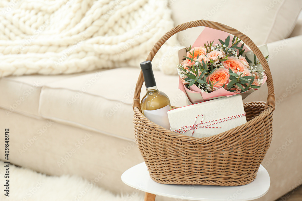 Wicker basket with gifts on table indoors. Space for text Wicker basket with gifts on table indoors. Space for text