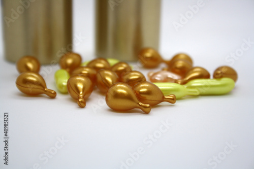 Gold and pink capsules with cosmetic oil for the face.