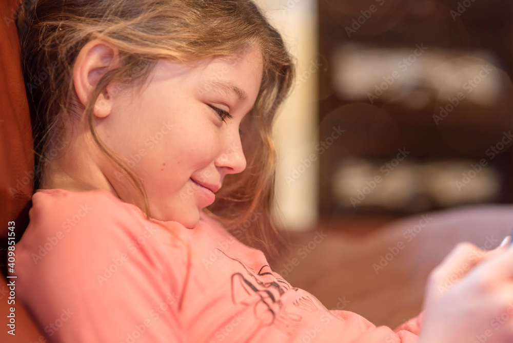 Pretty little girl playing or reading on a digital console or tablet Pretty little girl playing or reading on a digital console or tablet