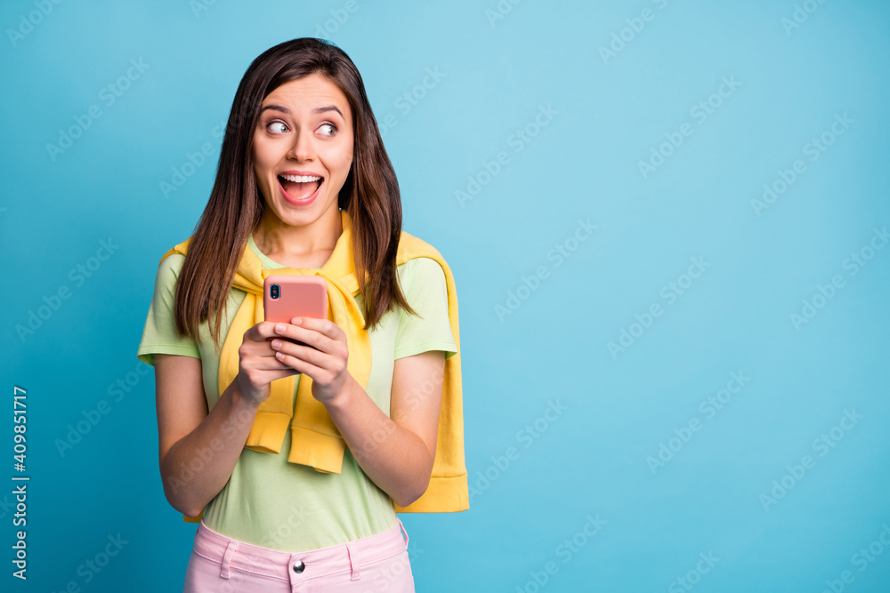 Photo of young happy crazy excited smiling cheerful positive girl use phone look copyspace isolated on blue color background Photo of young happy crazy excited smiling cheerful positive girl use phone look copyspace isolated on blue color background