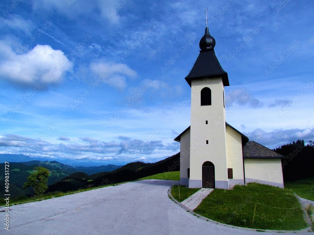 Church at Prtovc bellow Ratitovec in Gorenjska, Slovenia with a parking lot in front