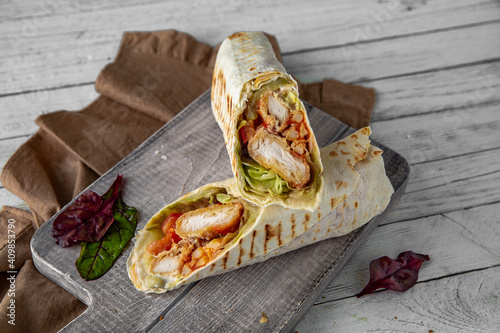 A delicious doner donair kebab wrap with chicken fillet, lettuce, tomato, onion and sauce.