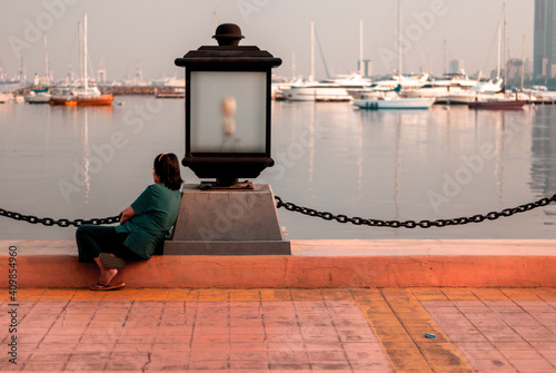 Old lady alone viewing the scene across a harbor   photo