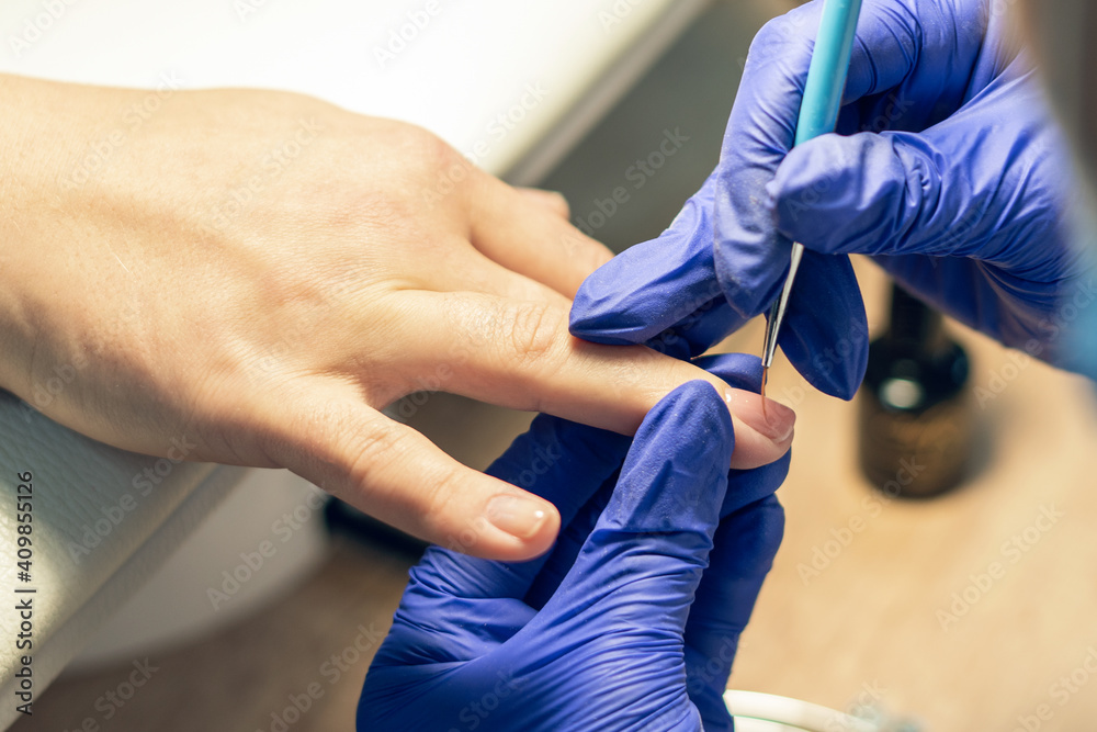 Manicurist doing a manicure in a nail salon, applying varnish on nails Manicurist doing a manicure in a nail salon, applying varnish on nails