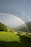 foggy mountain landscape with double rainbow and view to prattigau valley switzerland