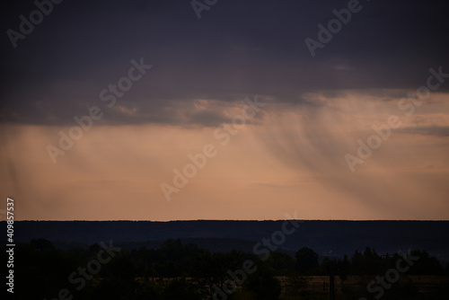 rain seen from afar at sunset. colored clouds on the horizon