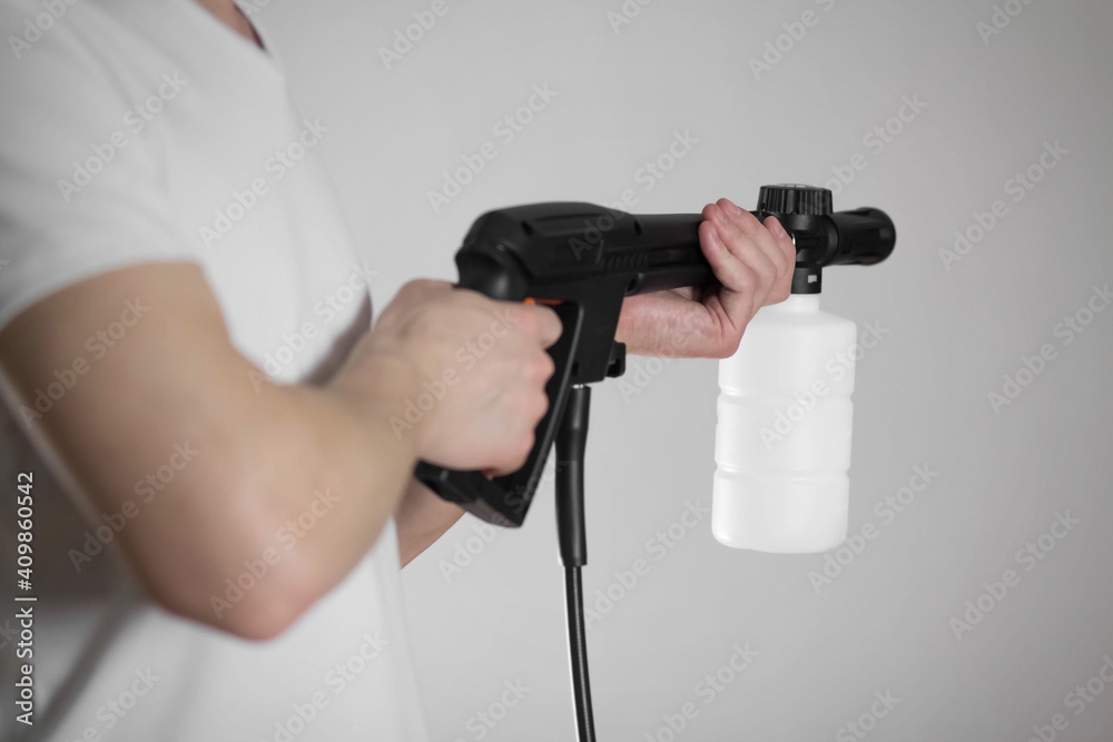 A man holds a high pressure washer. Close-up. Isolated on a gray background A man holds a high pressure washer. Close-up. Isolated on a gray background