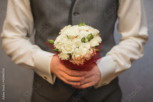 wedding small cute bouquet of white roses in the hands of the groom