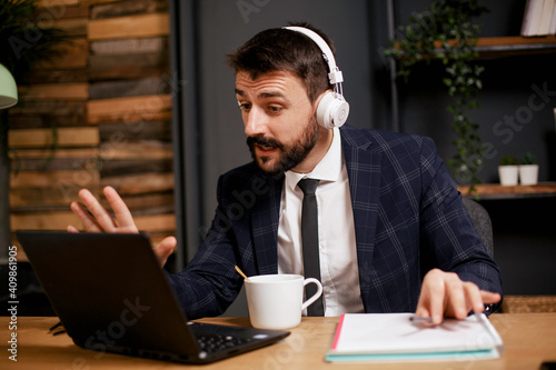 Young businessman working on laptop in his office. Handsome man having video call