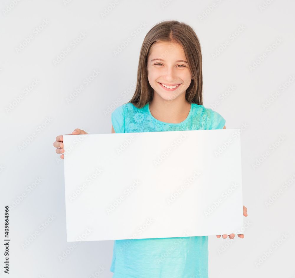 Young smiling girl holding blank sheet of paper, with free copy space Young smiling girl holding blank sheet of paper, with free copy space