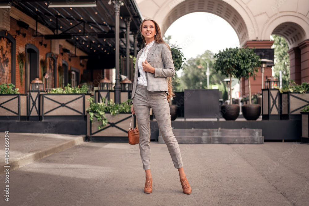 Business woman in a stylish suit in a cage walks down the street. model posing in lightweight outfit. Business woman in a stylish suit in a cage walks down the street. model posing in lightweight outfit.