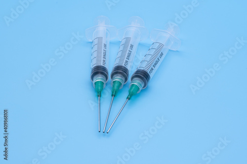 clear plastic syringes with needles isolated against a bue background photo