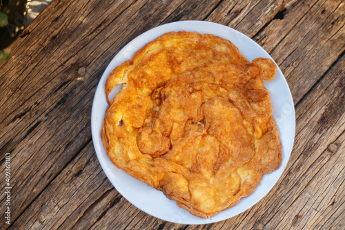 Crispy golden yellow omelette with plates on an old wooden floor is another simple dish in Thailand.