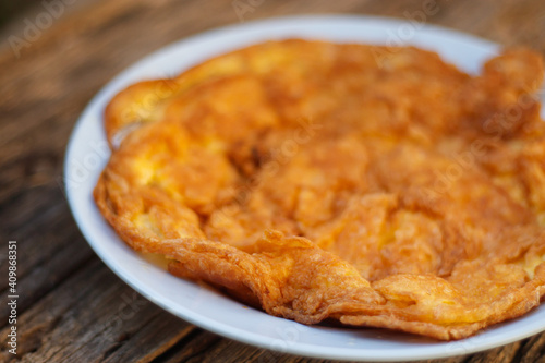 Crispy golden yellow omelette with plates on an old wooden floor is another simple dish in Thailand.