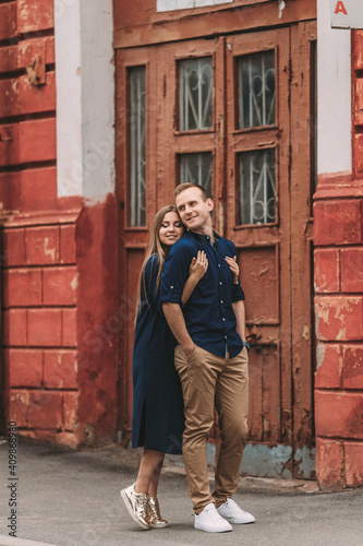 Happy beautiful young couple on the background of red old doors. Happy family concept