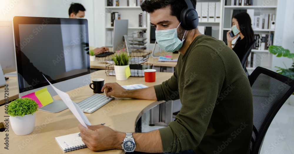 Busy businessman wearing facemask reading and check on business paper carefully in office Busy businessman wearing facemask reading and check on business paper carefully in office