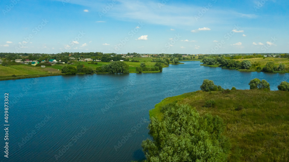 Scenic aerial view of river and green fields in Russian countryside. Natural landscape of the river curve and lush green trees.