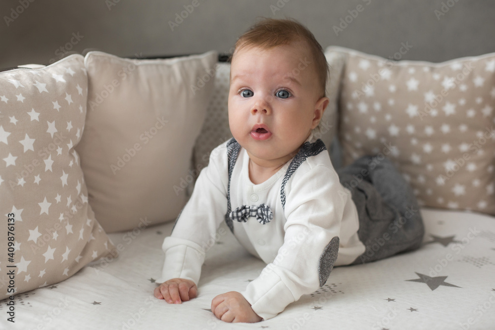 A cute little baby boy is surprised lying on the bed. Closeup portrait of newborn baby looking at camera A cute little baby boy is surprised lying on the bed. Closeup portrait of newborn baby looking at camera