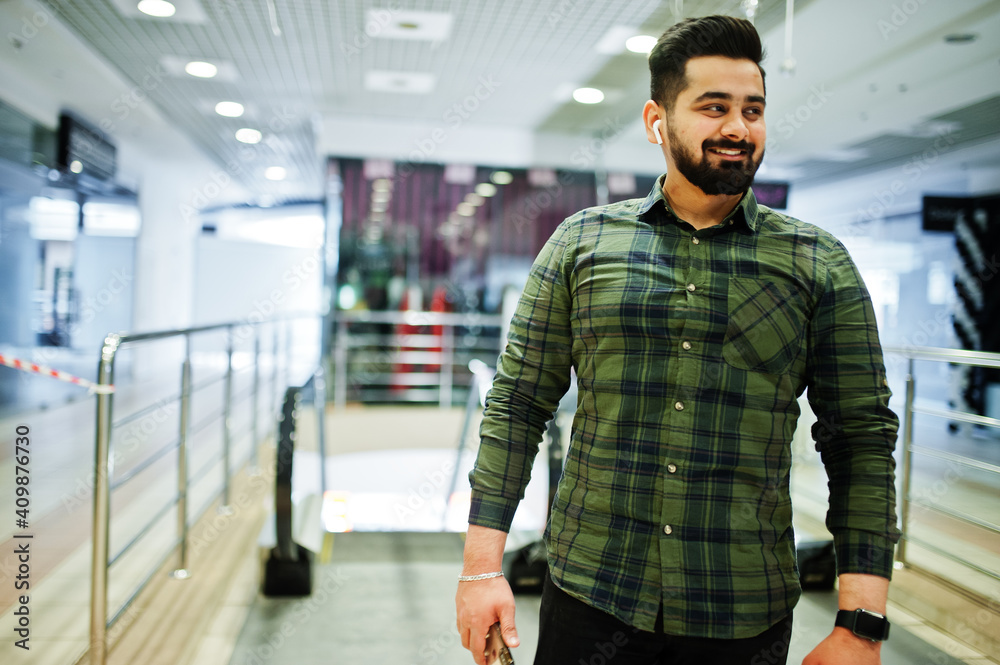 Beard indian guy with mobile phone pose at trade center against escalator. Beard indian guy with mobile phone pose at trade center against escalator.