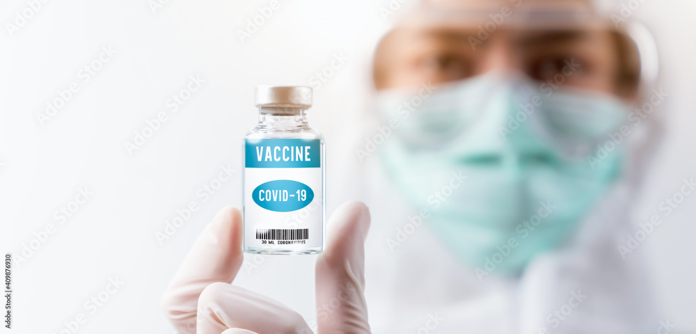 Scientist in PPE(personal protective equipment) and wear face mask protective gloves holding coronavirus vaccine in glass bottle on white background. Scientist in PPE(personal protective equipment) and wear face mask protective gloves holding coronavirus vaccine in glass bottle on white background.