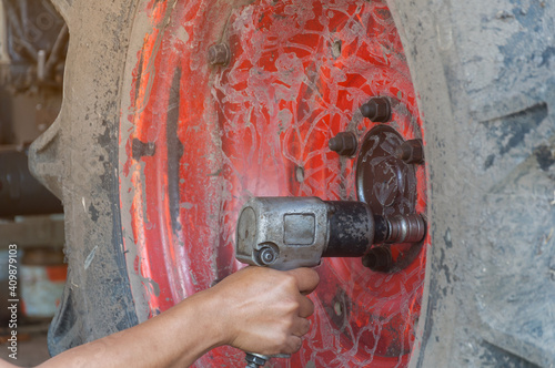 Hand of a professional tractor mechanic is removing the wheel nut.