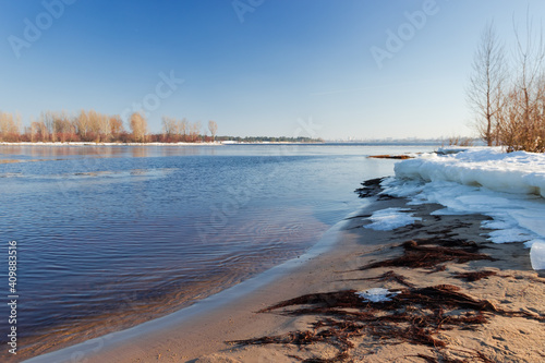Wide river partially covered with ice in early springtime