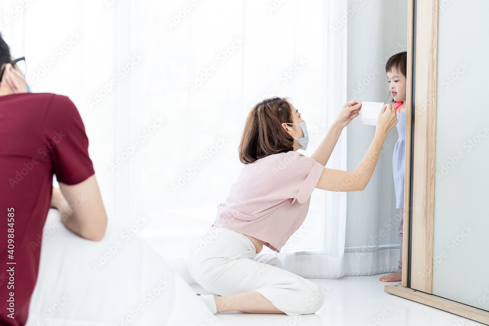 An Asian mother is wearing a mask for her daughter with a disabled development. An Asian mother is wearing a mask for her daughter with a disabled development.