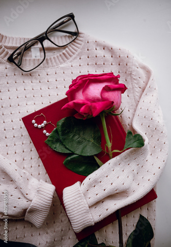 women's beige pullover lies on a white background with a red book, jewelry and a rose © Наталья Ржевская