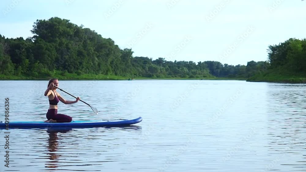 woman pushing and pulling the paddle through shining water surface and propelling paddleboard on sunny morning woman pushing and pulling the paddle through shining water surface and propelling paddleboard on sunny morning