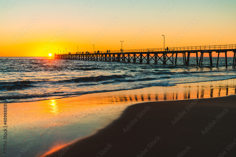 People silhouettes on Port Noarlunga jetty viewed from the beach at sunset, South Australia